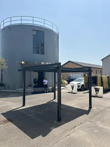 Pergola bioclimatica antracite davanti a un edificio